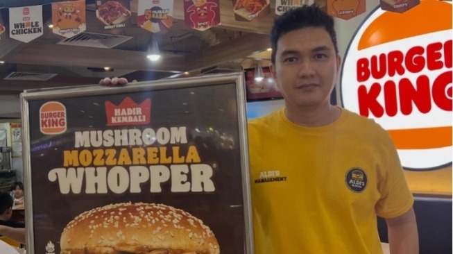 Aldi Taher memegang papan promosi burger di gerai Burger King saat promosi kuliner viral