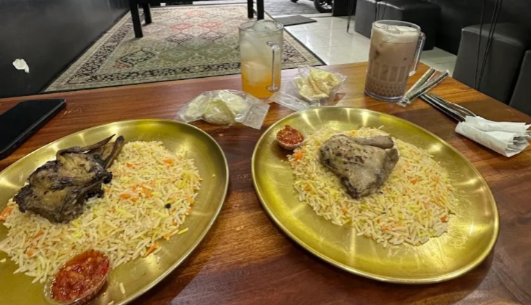 Dua porsi Nasi Kebuli kambing dan ayam dengan nasi basmati di atas piring emas khas Kebuli Abuya Taman Siswa Yogyakarta.